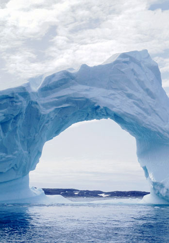 Stort blåt isfjeld med hul igennem. (Det er ikke fotografen der har lavet hærværk på isbjerget